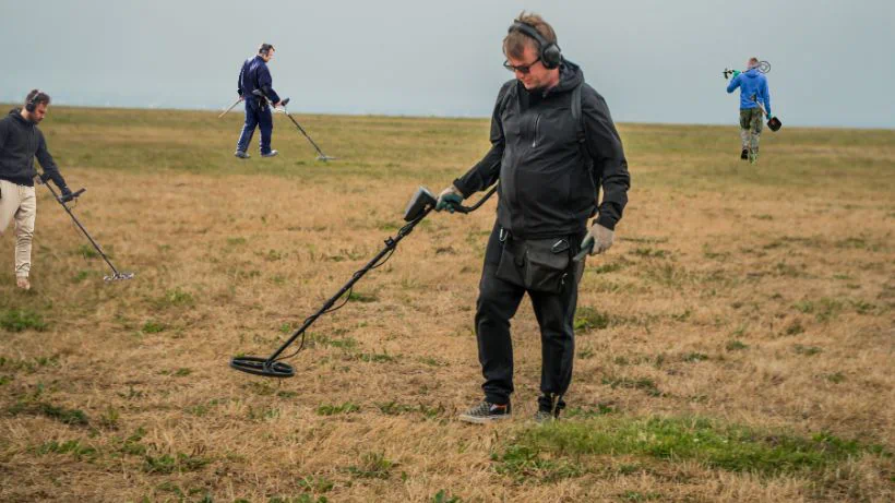 Vernetzt euch mit anderen Sondlern: Eine Gruppe von Sondengängern bei der gemeinsamen Suche mit Metalldetektoren auf einer Wiese.