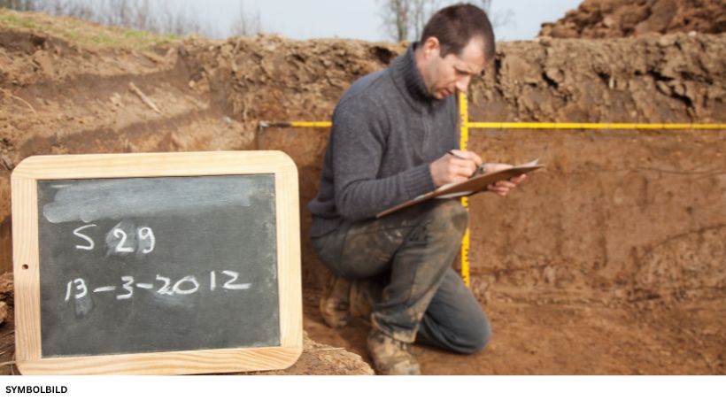Archäologische Grabung mit dokumentiertem Fund, Maßband und Fundtafel zur Erfassung von Lage und Tiefe